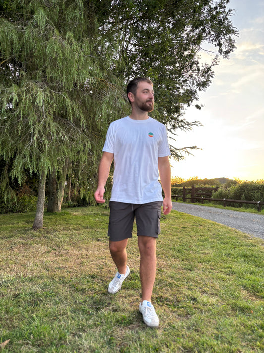 White t-shirt with a colorful logo on a wooden surface with records and books.