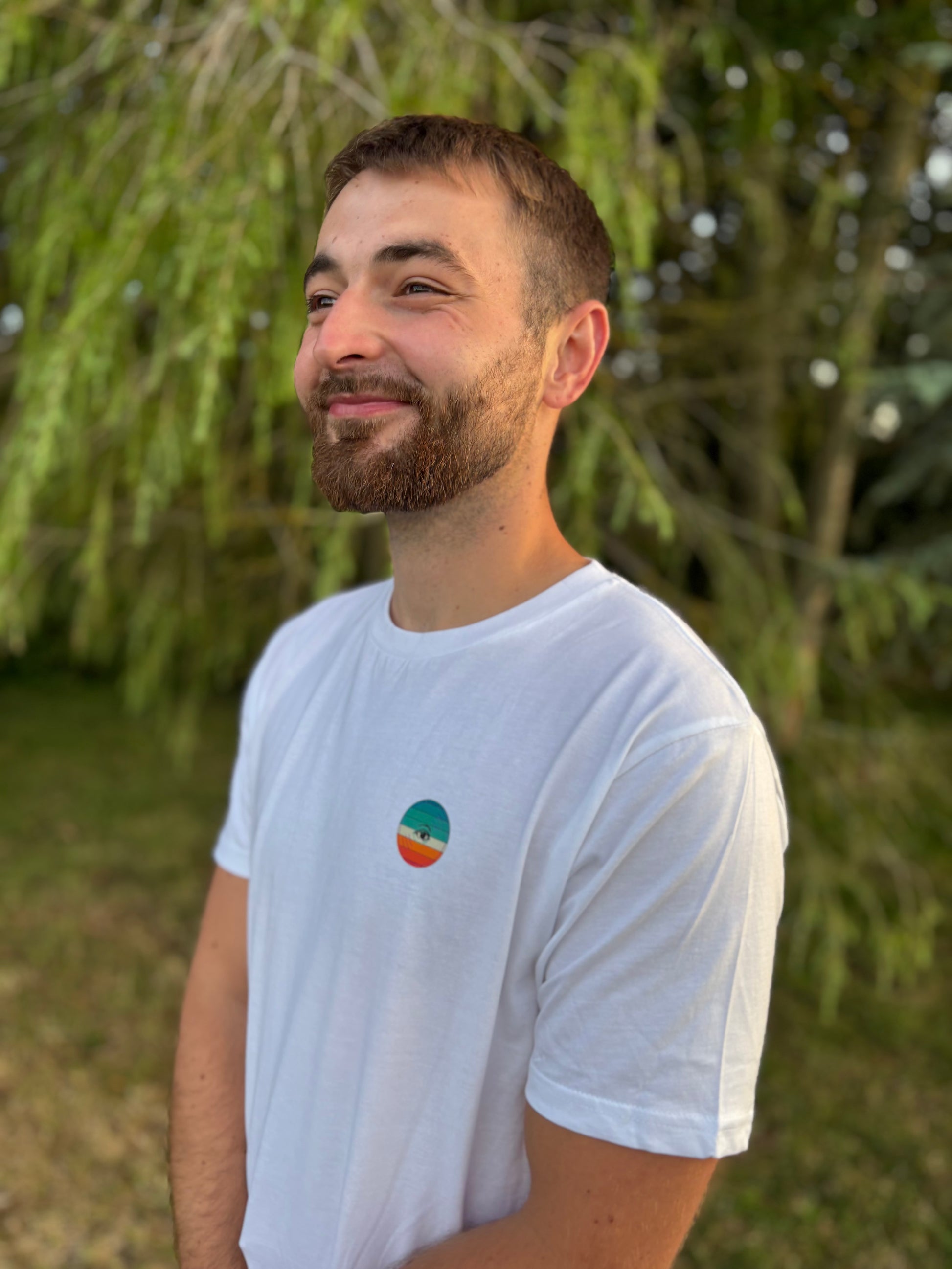 Man wearing a white t-shirt with a colorful logo outdoors