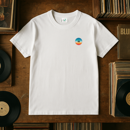 White t-shirt with a colorful logo on a wooden surface with records and books.